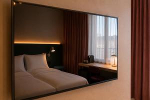 a mirror reflecting a bedroom with a bed and a desk at Hôtel Les Loges in Geneva