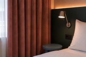 a bedroom with a bed and a red curtain at Hôtel Les Loges in Geneva +6 photos