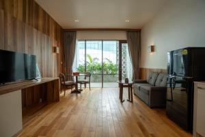 a living room with a couch and a tv and a table at Stadion Residences in Phumĭ Prêk Chrey