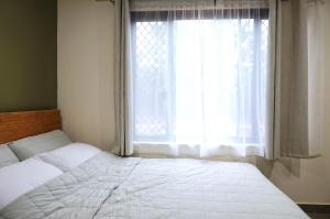 a bedroom with a white bed and a window at Emerald Oasis in Leanyer