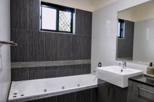 a bathroom with a sink and a tub and a mirror at Emerald Oasis in Leanyer