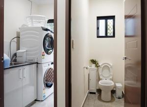 a bathroom with a washing machine and a toilet at Emerald Oasis in Leanyer