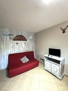a living room with a red couch and a piano at PINK House in Schilpario