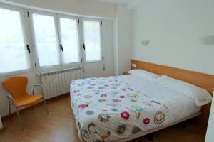 a bedroom with a bed and a chair and windows at Apartamentos Grosen in San Sebastián