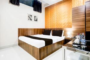 a bedroom with a bed with a wooden headboard at Hotel Swarat by TruStay in Satna