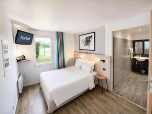 a hotel room with a white bed and a bathroom at Kyriad Hôtel La Fleche in La Flèche