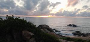 a sunset over the ocean with rocks in the water at Secret Point Luxury Glamping in Panama