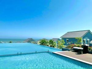 a swimming pool in front of a house with the ocean at ACIS SmartHome NovaWorld in Bình Tú