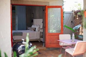 a bedroom with a bed and a table and a door at Ambiance Guesthouse in Pretoria +23 photos