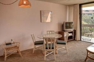 a living room with a table and chairs and a tv at Maui Vista 2207 in Kihei