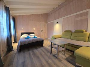 a bedroom with a bed and a couch and a table at Siedlisko Bartek domki na Kaszubach nad jeziorem Mausz in Sulęczyno