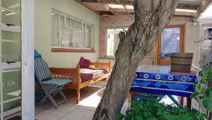 a porch with a bed and a table and a tree at The Willow Cottage in Cape Town