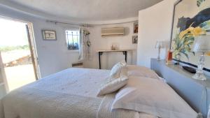 a white bedroom with a bed and a window at Villa Pibinson 3 chambres - piscine in Mougins +24 photos