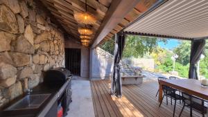 a patio with a stone wall and a table and a kitchen at Villa Pibinson 3 chambres - piscine in Mougins