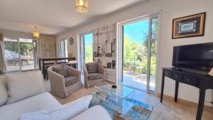 a living room with a white couch and a tv at Villa Pibinson 3 chambres - piscine in Mougins