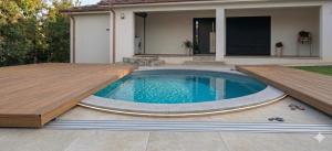a swimming pool with a wooden deck next to a house at Casa Machado in Cabeceiras de Basto