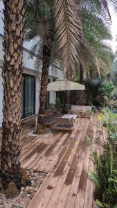 a wooden deck with two palm trees and an umbrella at amarzito villa in Dona Paula