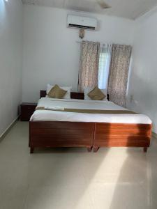 a large wooden bed in a room with a window at villas alleppey in Alleppey