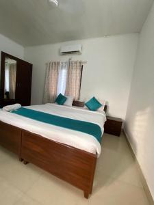 a bedroom with a large bed with blue pillows at villas alleppey in Alleppey