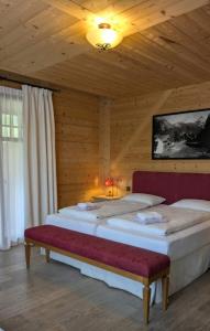 two beds in a wooden room with a ceiling at Guesthouse Hotel Between in Chamoson