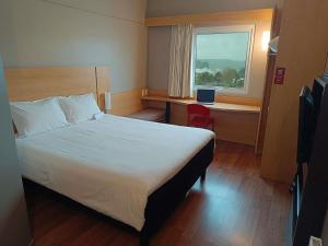 a bedroom with a bed and a desk and a window at ibis Puerto Montt in Puerto Montt
