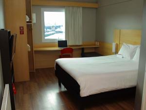 a hotel room with a bed and a desk and a window at ibis Puerto Montt in Puerto Montt