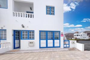a white building with blue doors and mountains in the background at Casa Suso y Casa Margarita- Orzola Coastal Retreat by LVH in Órzola +49 photos