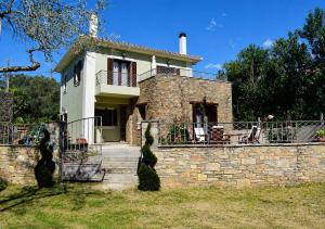 a house with a stone retaining wall and a staircase at Villa iliotropio in Lefokastro