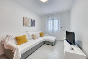 a white living room with a couch and a tv at Casa Suso y Casa Margarita- Orzola Coastal Retreat by LVH in Órzola