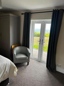 a bedroom with a bed and a chair and a window at Chevin End Guest House in Otley