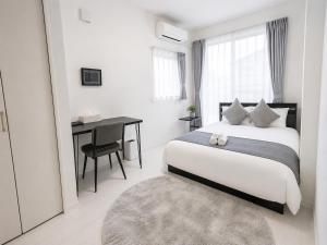 a white bedroom with a bed and a desk at Miyako Beach Resort in Hirara
