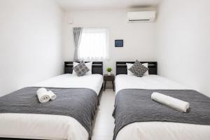 two beds in a room with white walls at Miyako Beach Resort in Hirara +43 photos