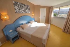 a bedroom with a large bed with a blue headboard at Hotel Drago Park by Pierre & Vacances in Costa Calma