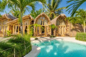 a tropical home with a swimming pool and palm trees at Mare Eco Bungalows - Kids & Family friendly in Kuta Lombok