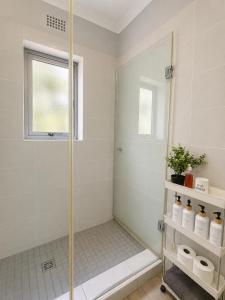 a shower with a glass door in a bathroom at Stay on Main - Studio Blue in Paarl