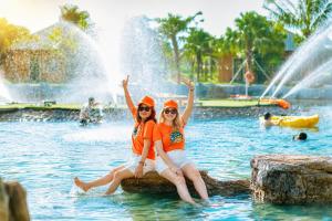 two girls sitting on a log in the water at a water park at Cuc Phuong Tropical Villas in Thượng Sung