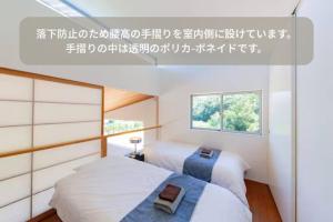 two beds in a small room with a window at The SATOYAMA HILLS FK1 in Futtsu