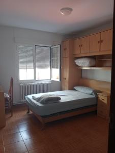 a bedroom with a bed and two windows at Casa Oskar in Avilés
