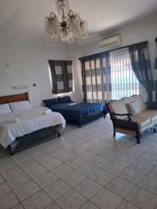 a bedroom with two beds and a couch and a chandelier at Nomty House in Durban
