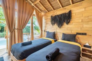 two beds in a room with wooden walls and windows at Mare Eco Bungalows - Kids & Family friendly in Kuta Lombok +95 photos