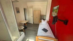 a small room with a bed and a red wall at Hotel und Gaststätte zum Grafenwall in Recklinghausen