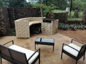 a patio with two chairs and a brick fireplace at Roundhouse Marloth Park in Marloth Park