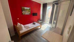 a small red room with a bed and a window at Hotel und Gaststätte zum Grafenwall in Recklinghausen