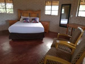 a bedroom with a large bed and two chairs at Roundhouse Marloth Park in Marloth Park