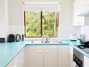 a white kitchen with a sink and a window at Fathoms 5 - 2BR beach resort apartment in Mollymook