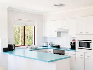 a kitchen with white cabinets and a blue counter top at Fathoms 5 - 2BR beach resort apartment in Mollymook