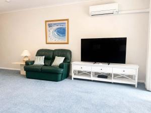 a living room with a green chair and a flat screen tv at Fathoms 5 - 2BR beach resort apartment in Mollymook +9 photos