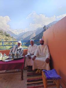 three priests sitting on a balcony with a view of mountains at Imlil agarssiwal in Aguersioual