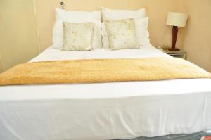 a large white bed with white sheets and pillows at Lhondeh Apartments in Livingstone