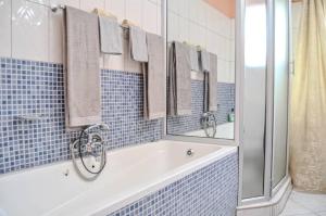 a blue tiled bathroom with a tub and mirrors at Lhondeh Apartments in Livingstone